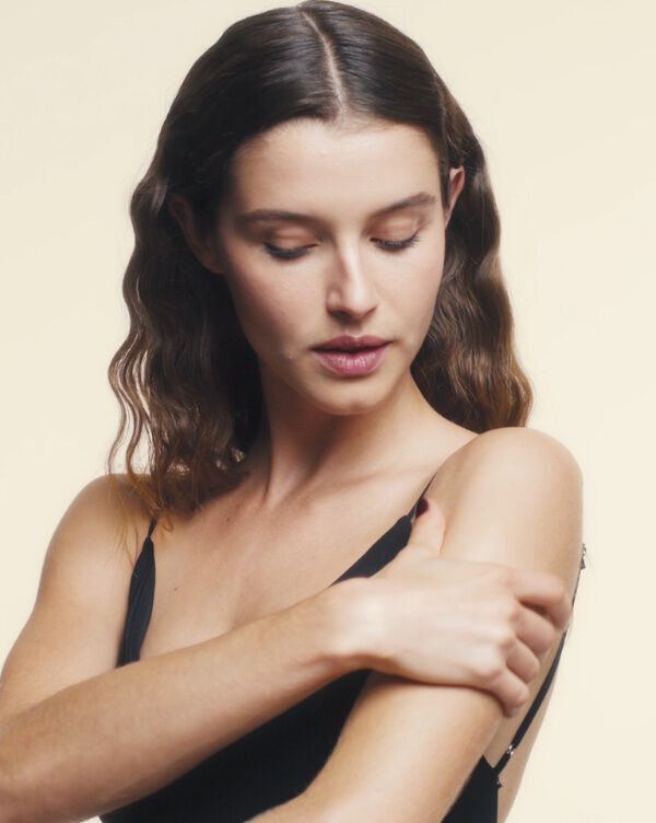 Le mani di una donna che le massaggiano la spalla con dell'olio.