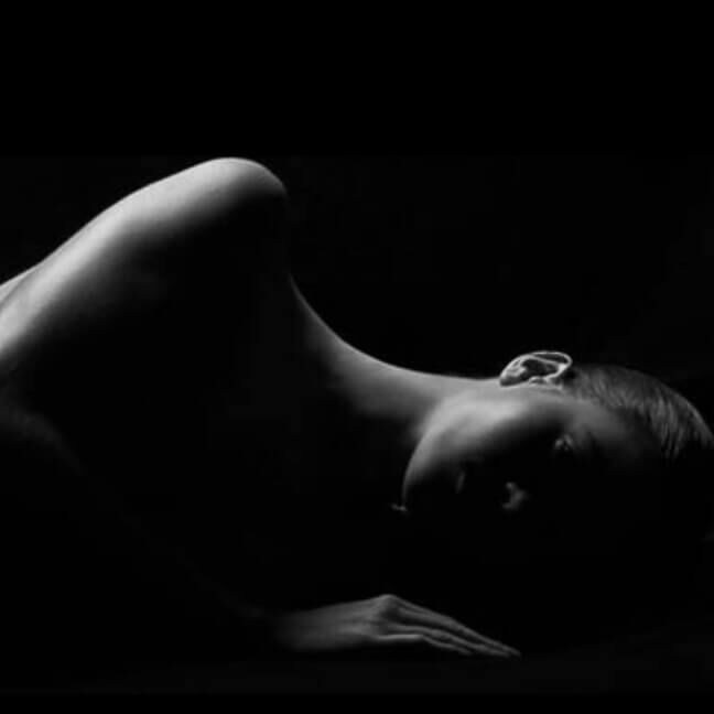 La sagoma di una figura sdraiata su uno sfondo nero, che mette in risalto le curve e le linee morbide del corpo.