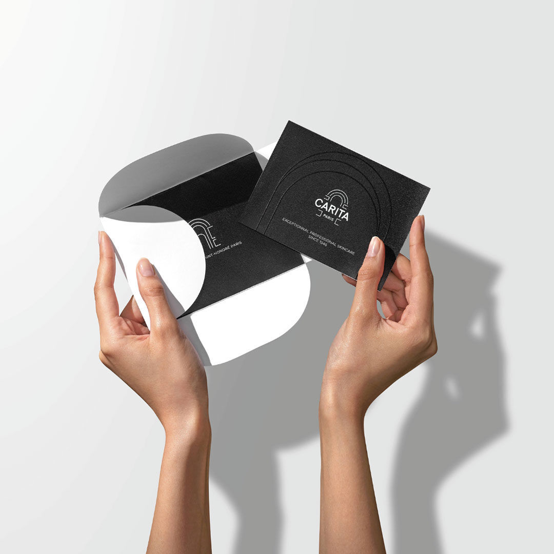 Mani che aprono un astuccio nero contenente una carta regalo nera.