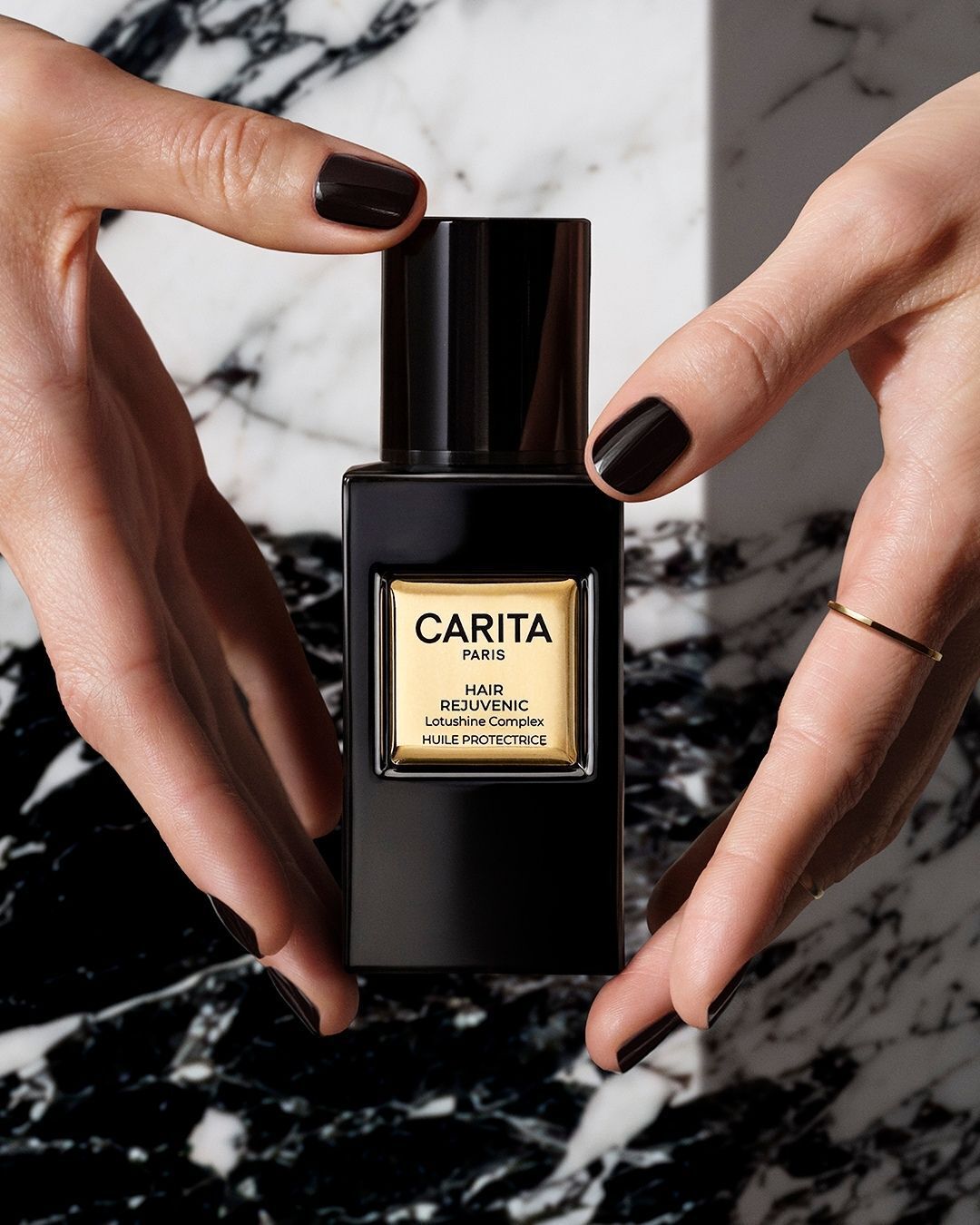 Mani che stringono il flacone dell’Olio Lumino-Protettivo Carita.