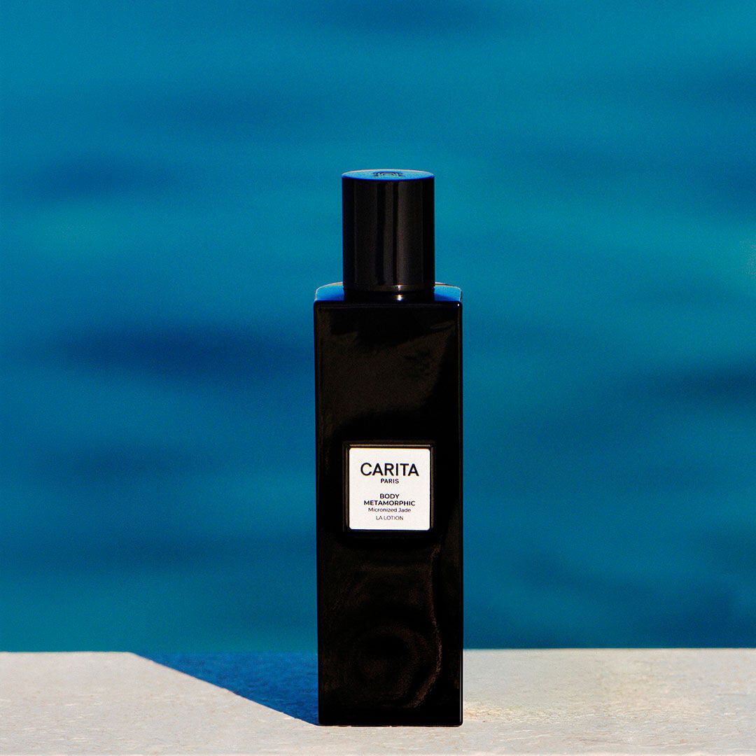 Flacone nero della lozione Body Metamorphic su sfondo azzurro.