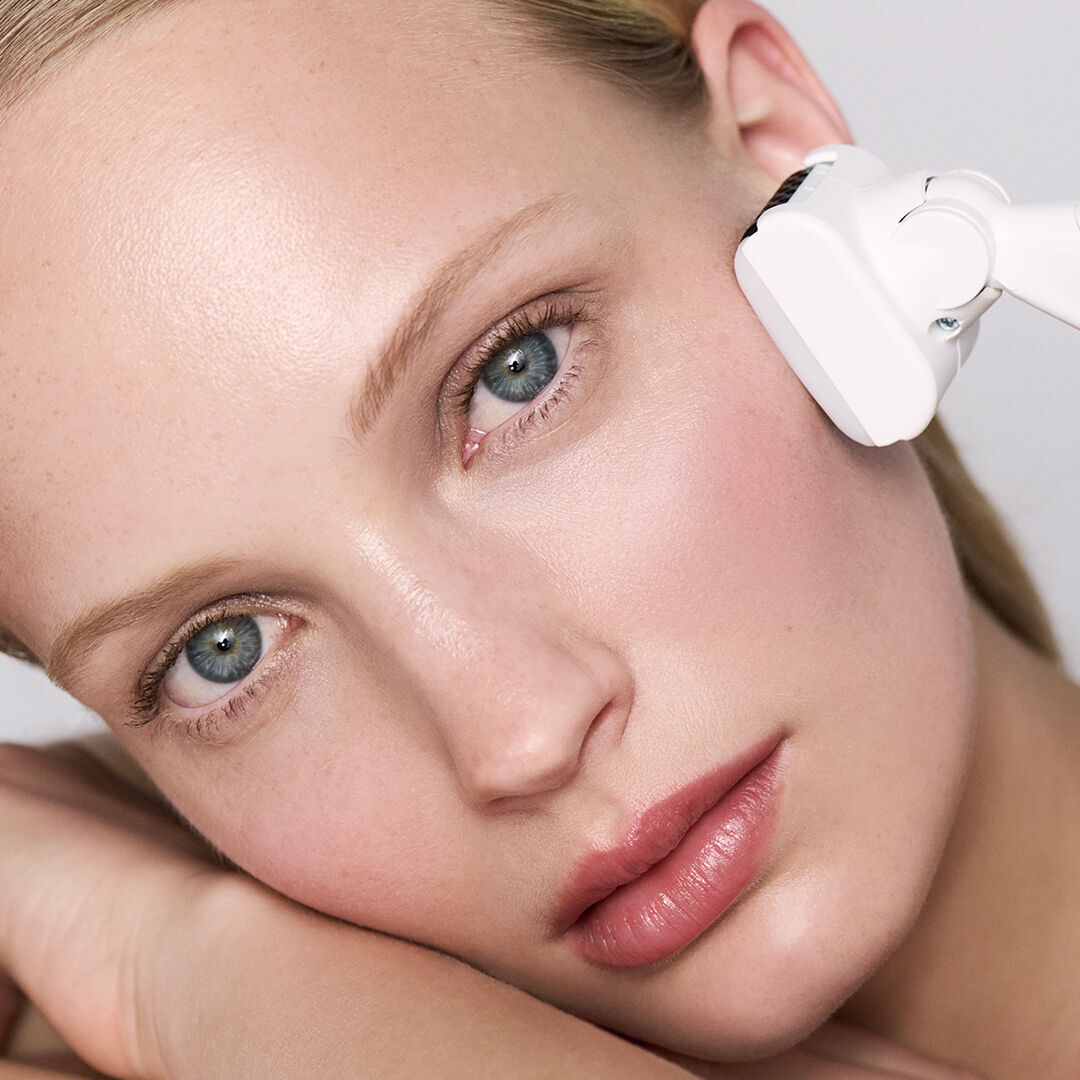 Donna che riceve un trattamento viso con un dispositivo bianco.