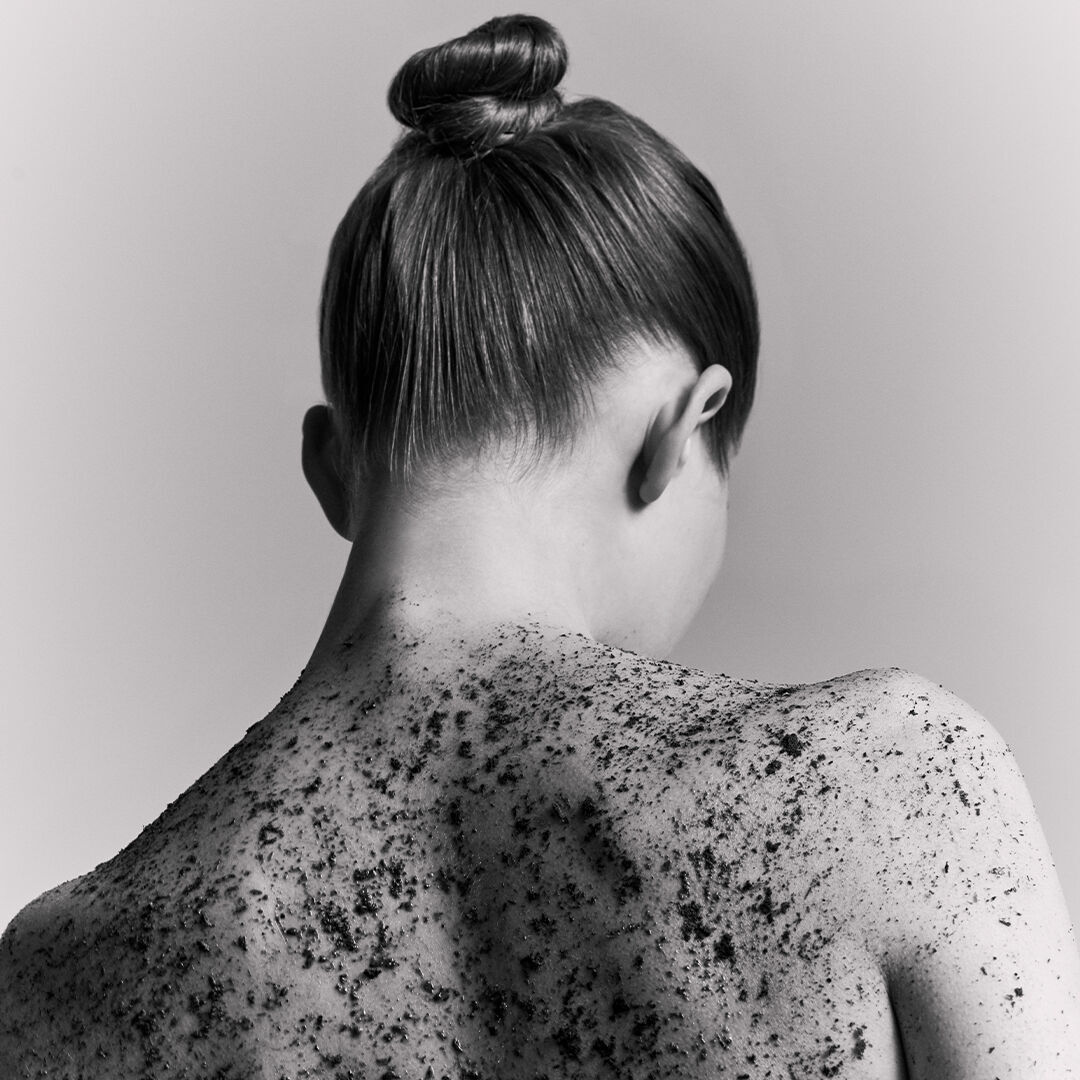 Ritratto di schiena di una donna con uno scrub dalla texture granulosa.