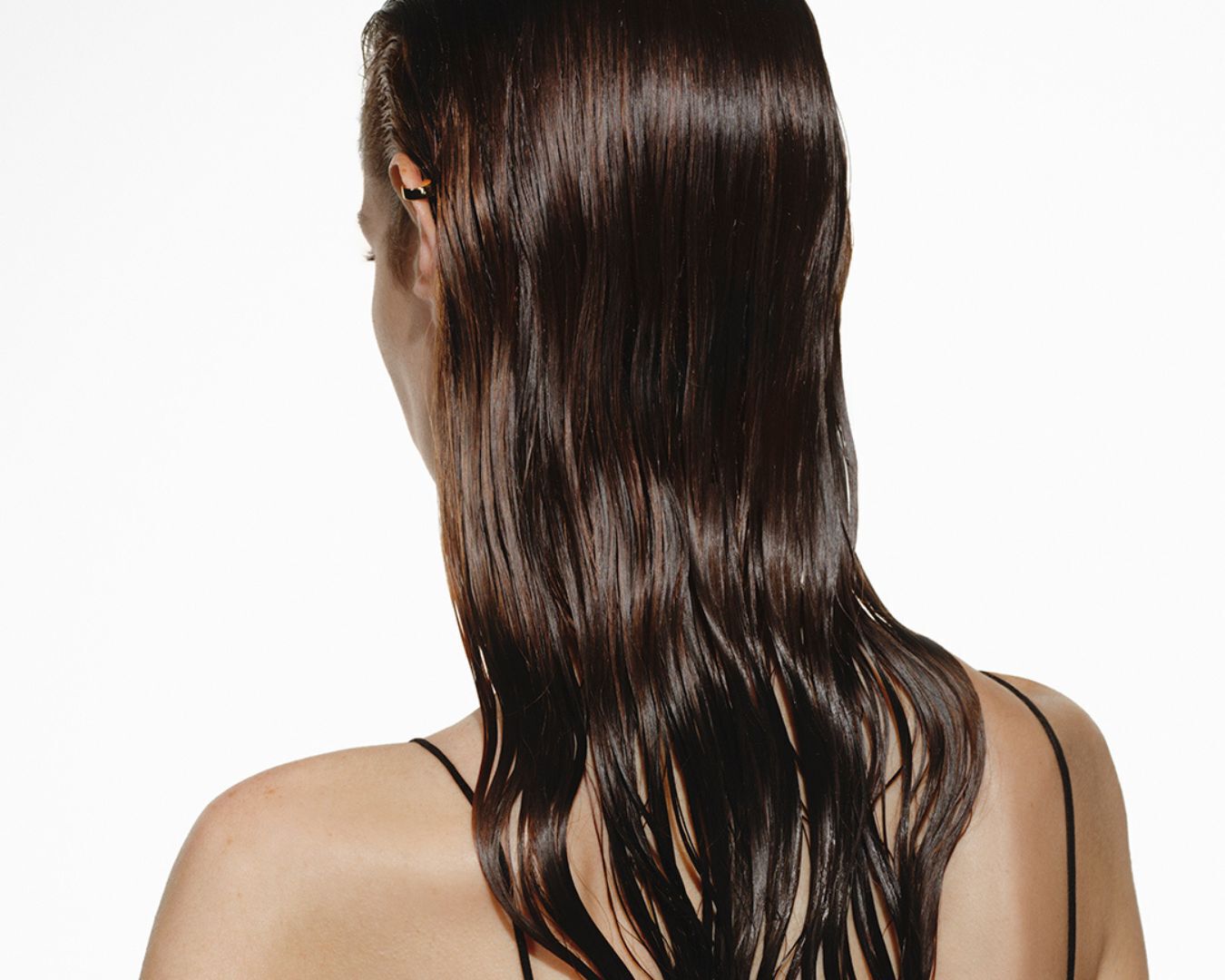 La schiena di una donna dai lunghi capelli castani, umidi e mossi.