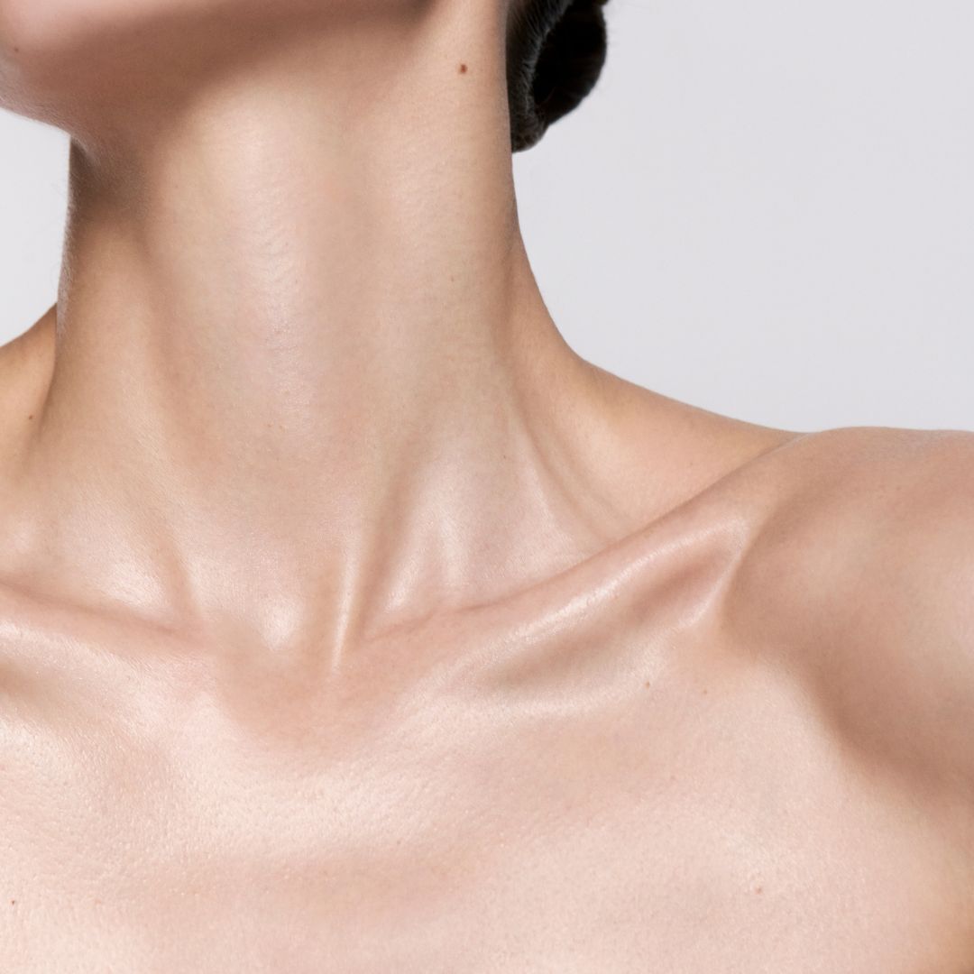 Primo piano sul collo e sulla clavicola nudi e illuminati di una donna.