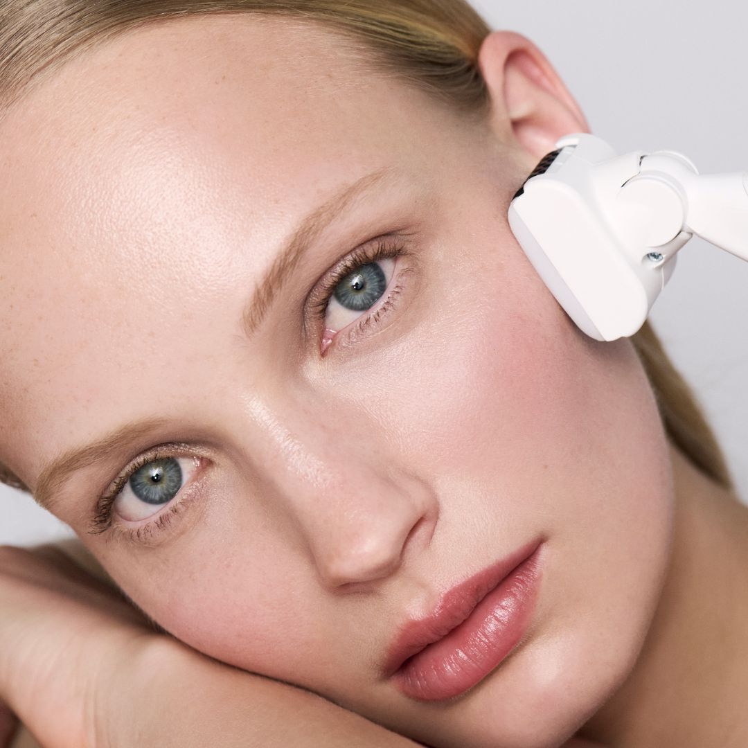 Donna che si sottopone a un trattamento viso con un apparecchio estetico bianco.