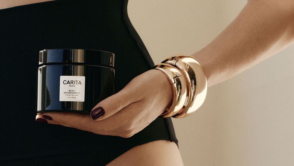 Donna in costume da bagno che tiene in mano il vaso Body Metamorphic.