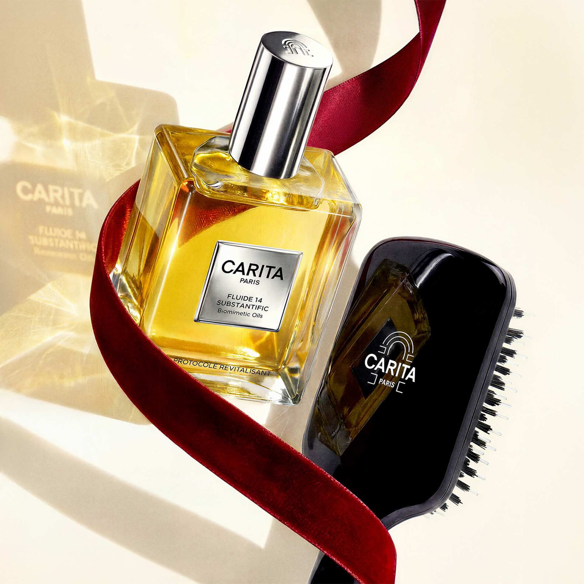 Composizione lussuosa con il flacone dorato di Fluide 14 Substantific e una spazzola nera Carita, impreziositi da un nastro di velluto rosso.